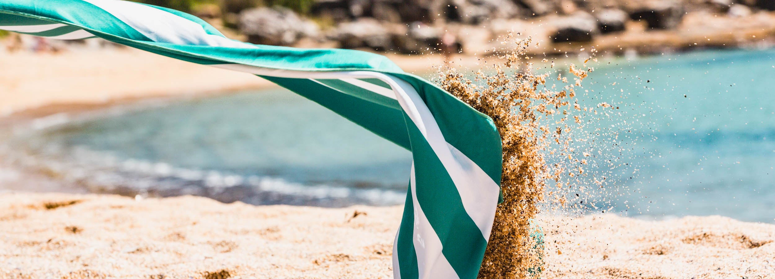 Sand flying off a sand free beach towel