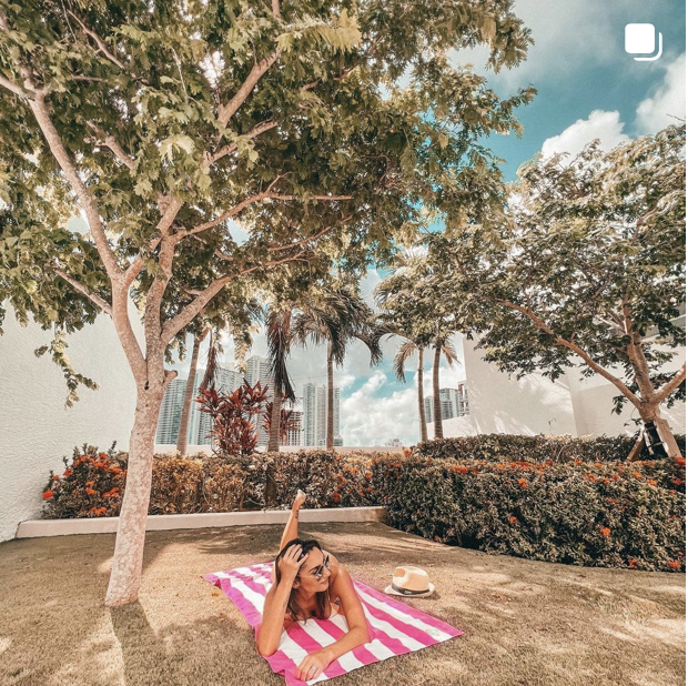 Woman lying down on a fuchsia striped beach towel 