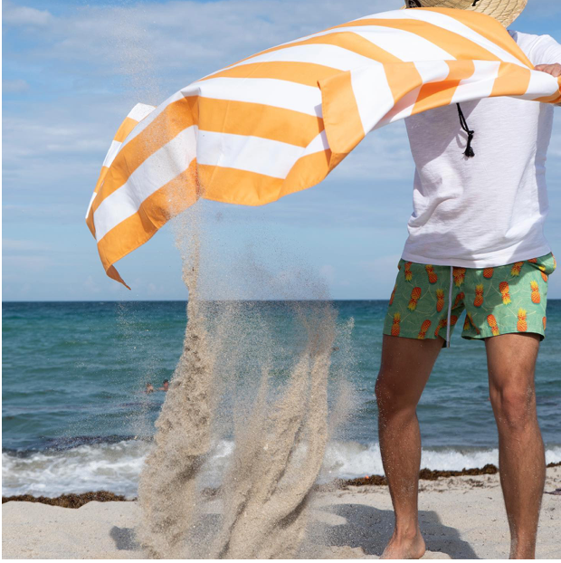 Person shaking off sand from a beach towel